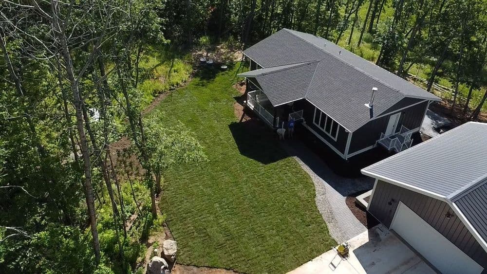 Aerial view of a modern home surrounded by lush greenery and a well-maintained lawn.