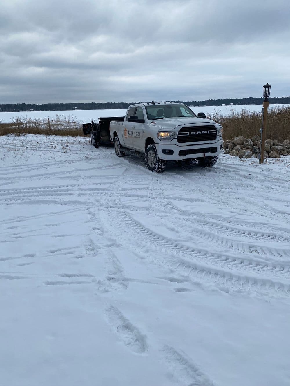 Dodge RAM truck parked in snowy landscape near frozen lake with snow-covered grass.