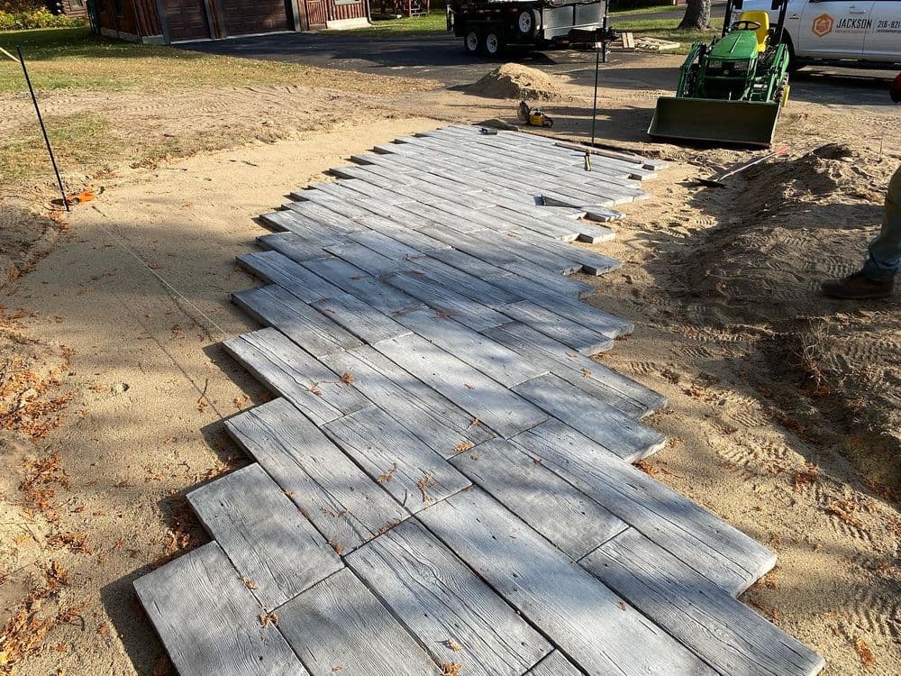 Curved wooden walkway installation on sandy landscape, surrounded by construction equipment.
