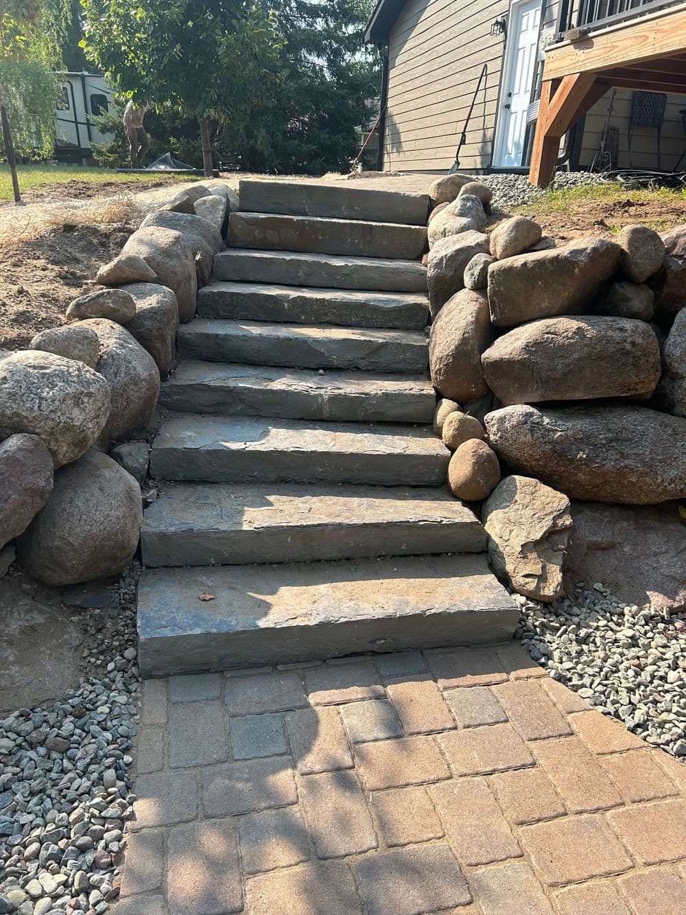 Natural stone steps leading to a house surrounded by landscaped rocks and gravel.