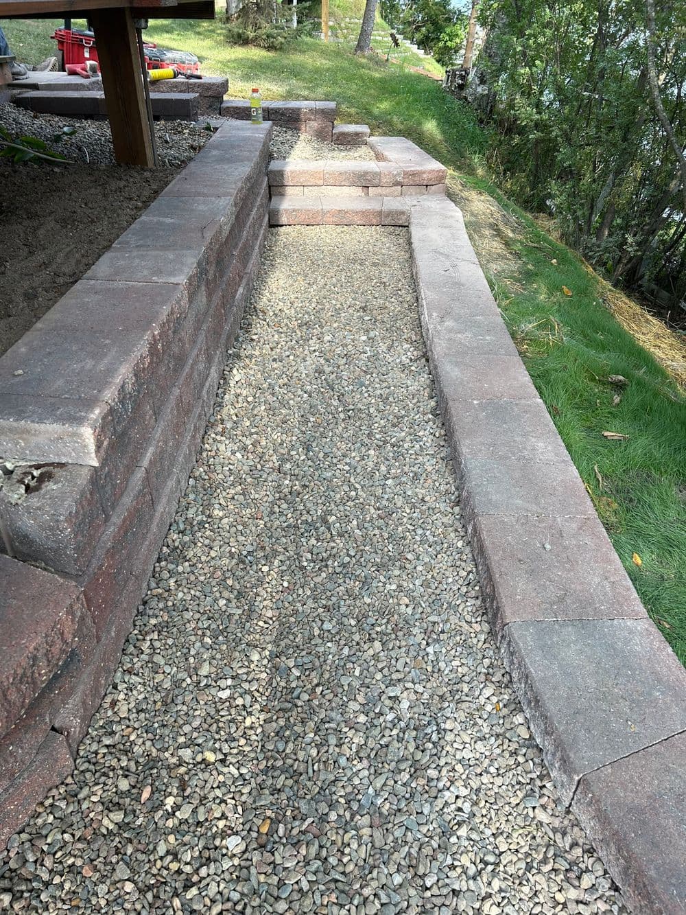Retaining wall pathway made of stone with gravel surface in a landscaped yard.