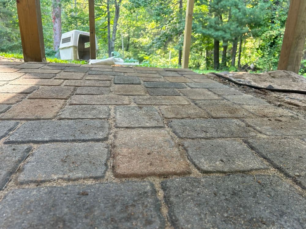 Paved stone patio with greenery in the background, showcasing a serene outdoor space.