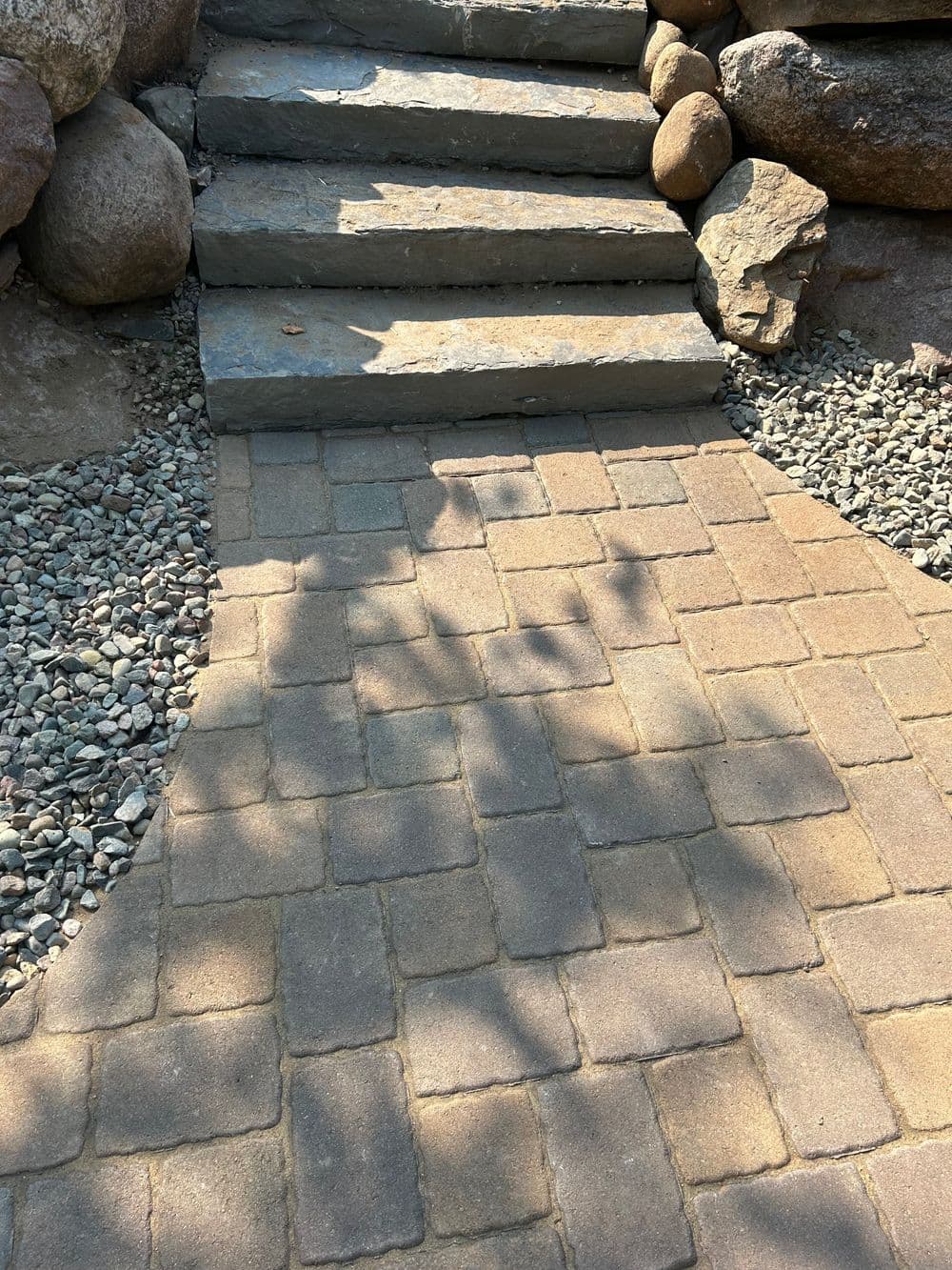 Stone steps leading up a garden pathway with gravel and rocks on either side.
