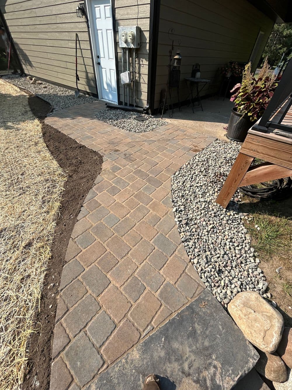 Paved walkway leading to a house, landscaped with gravel and plants for curb appeal.