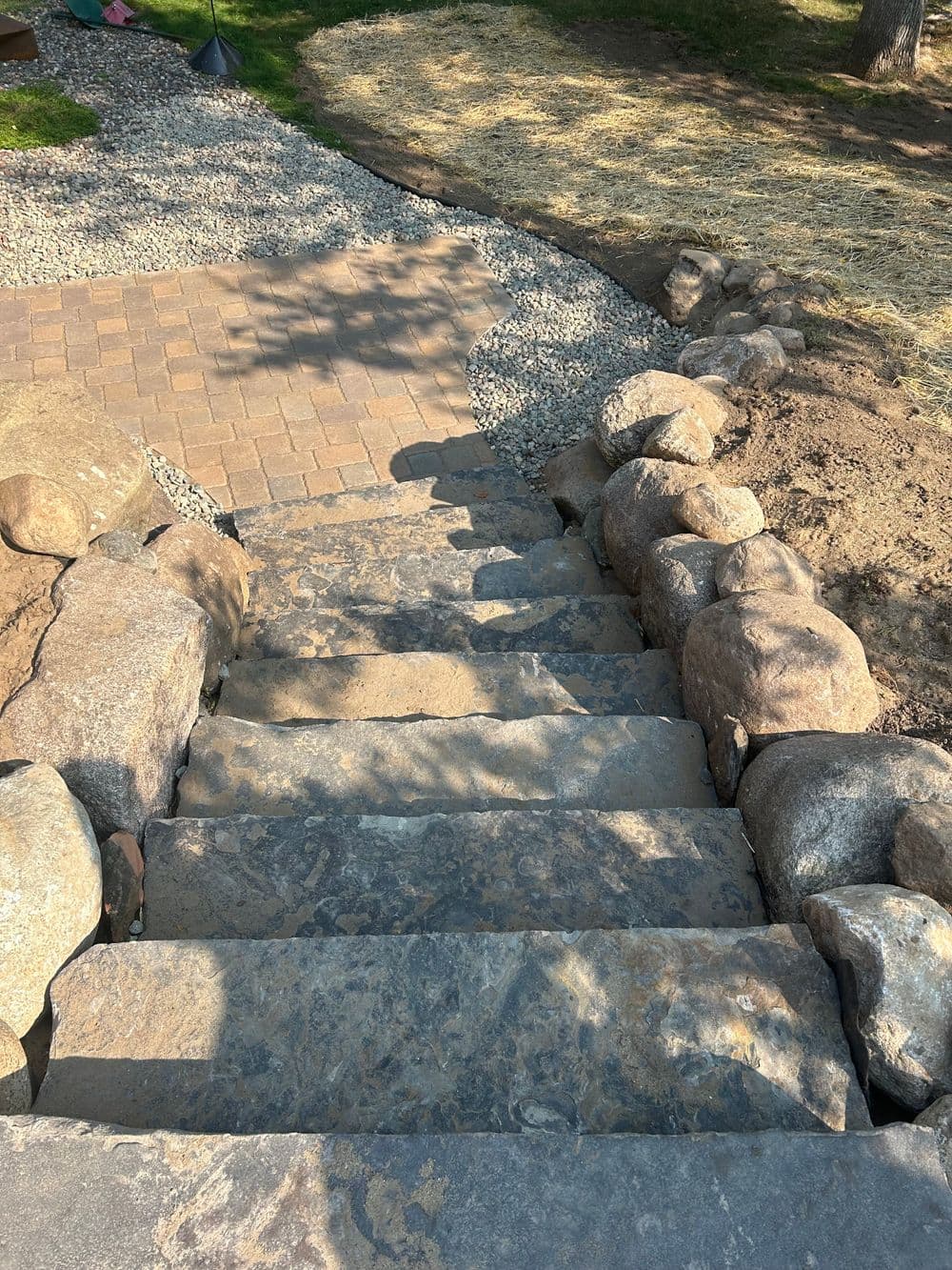 Stone steps leading down a landscaped pathway with gravel and grass beside them.