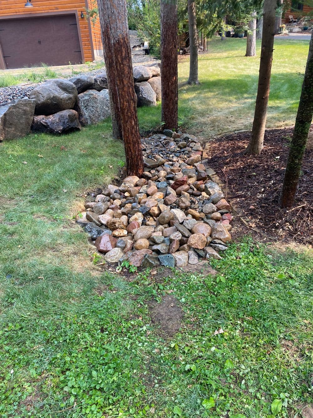 Rock garden path surrounded by trees and grass, featuring a variety of colorful stones.