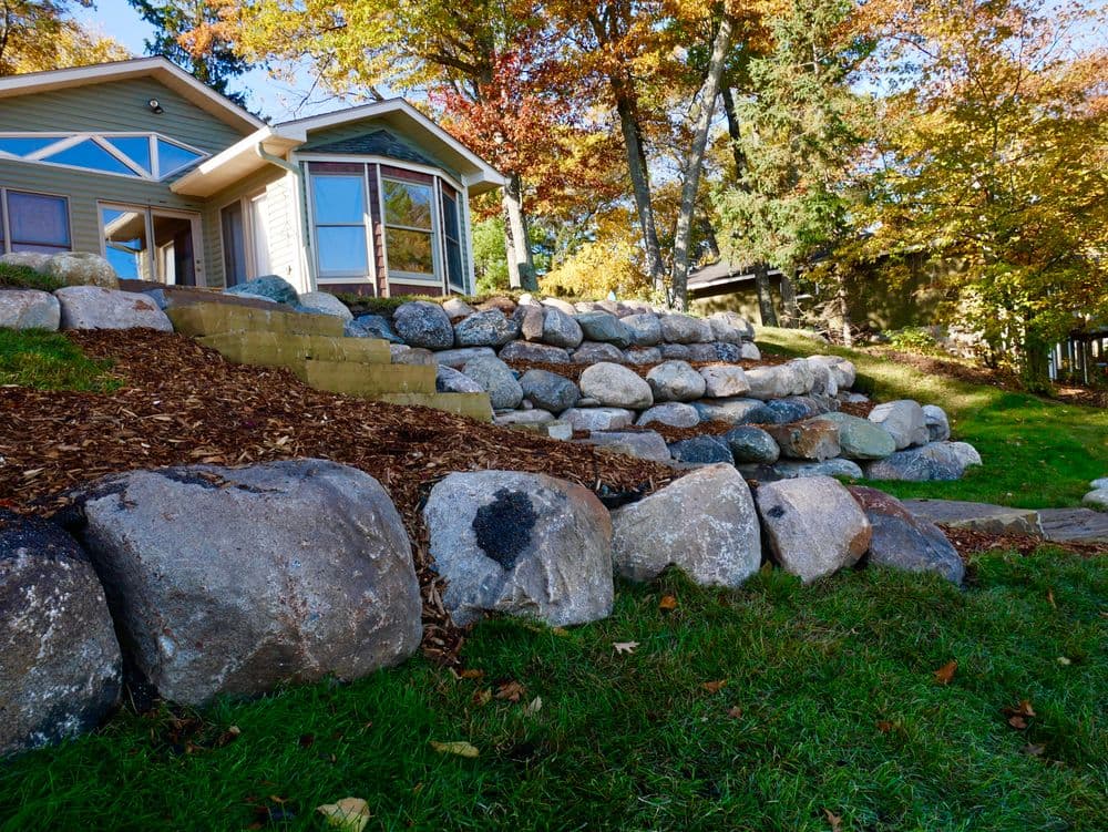 Stunning landscape with a stone terrace and vibrant autumn foliage near a cozy home.