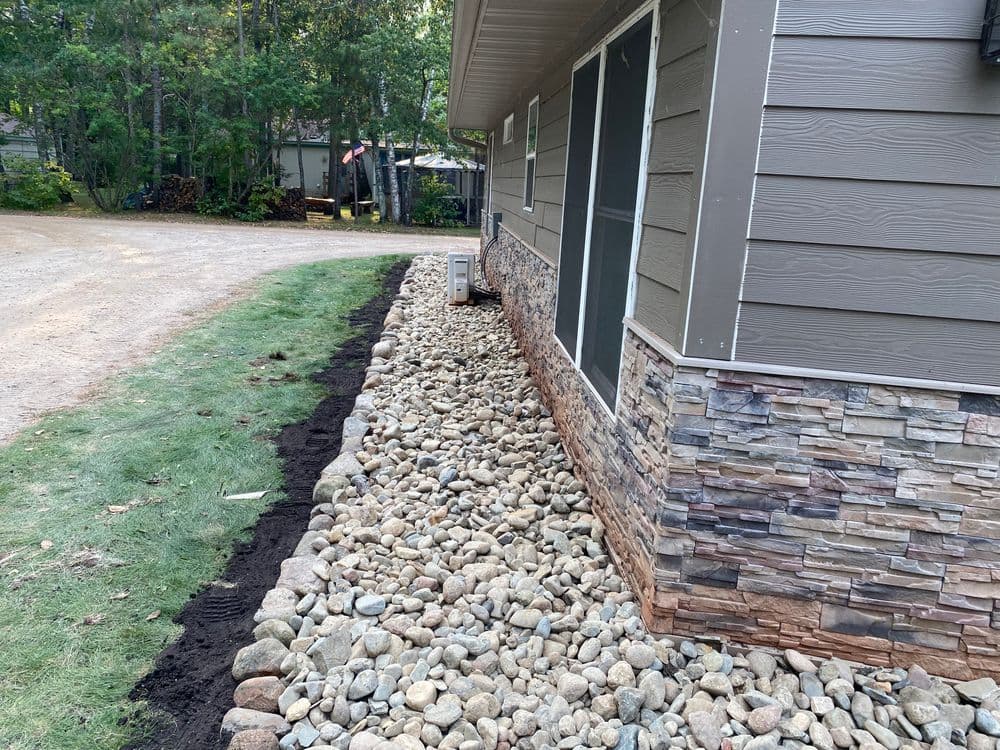 Landscaped home exterior featuring stonework and decorative gravel along the foundation.