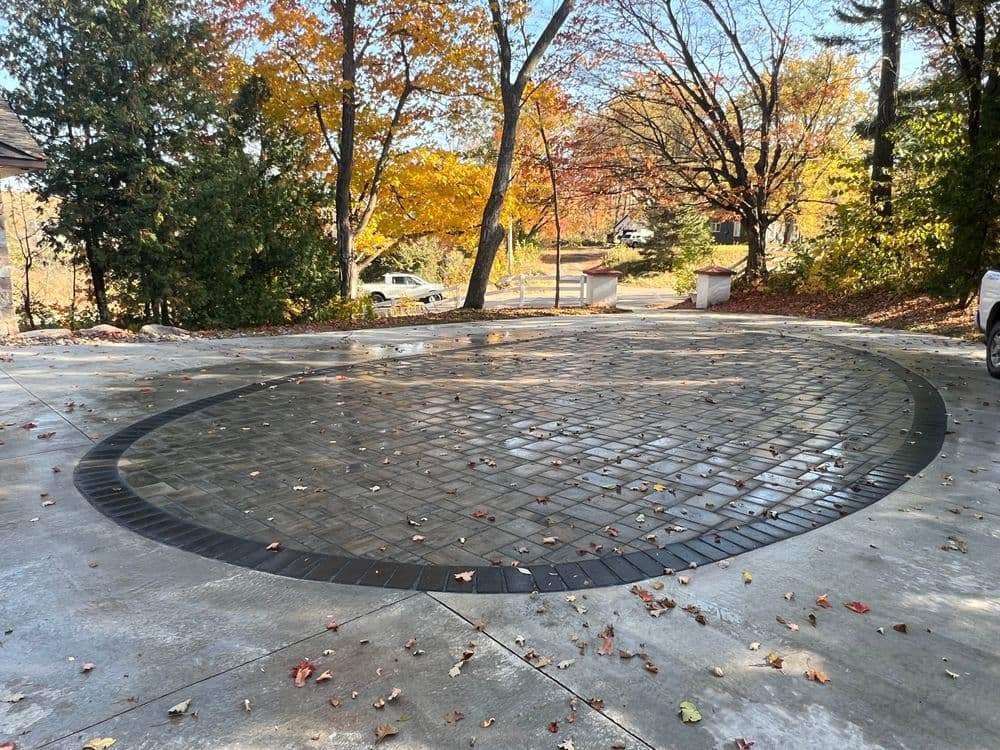 Circular patterned driveway surrounded by autumn trees and scattered leaves.