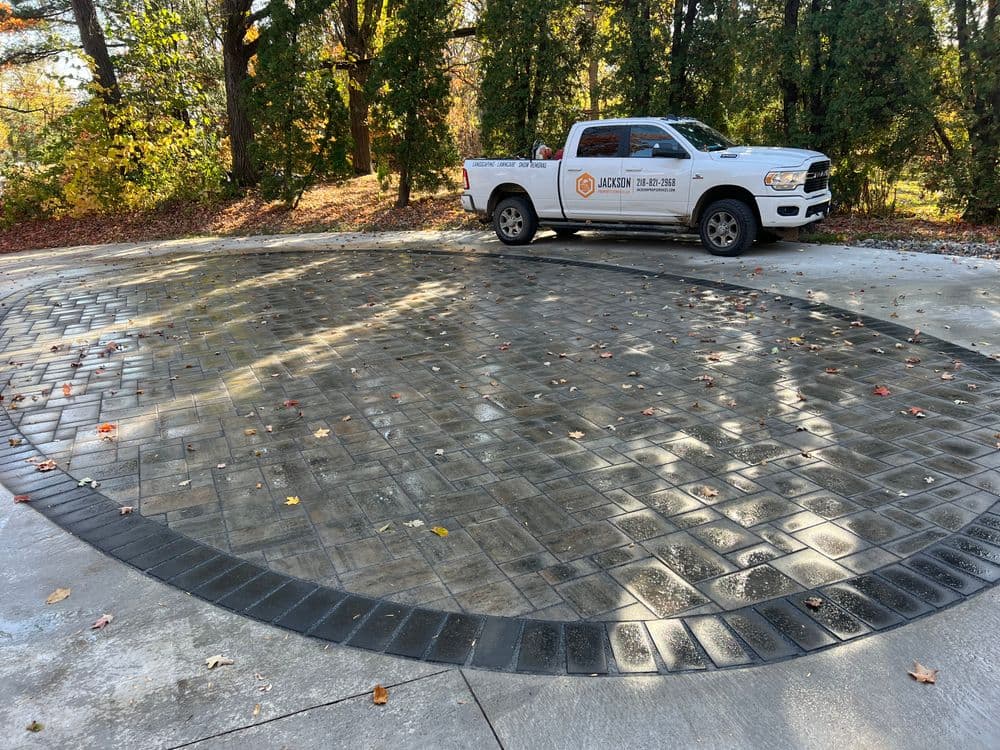 Newly installed circular concrete driveway with decorative borders and a work truck nearby.